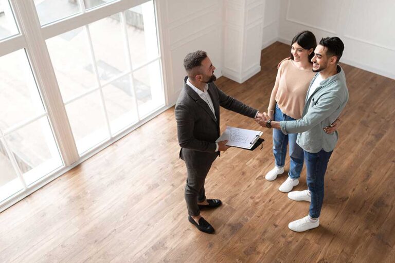 A couple reviews home inspection paperwork in the living room of a single-family house with moving boxes nearby.